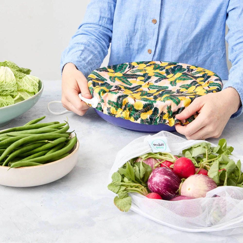 Person holding a reusable bowl cover on a blue bowl