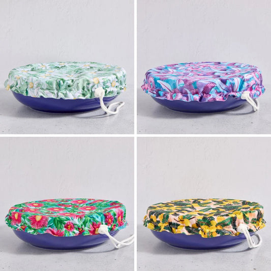 Four floral-patterned reusable bowl covers on a bowls against a light grey background