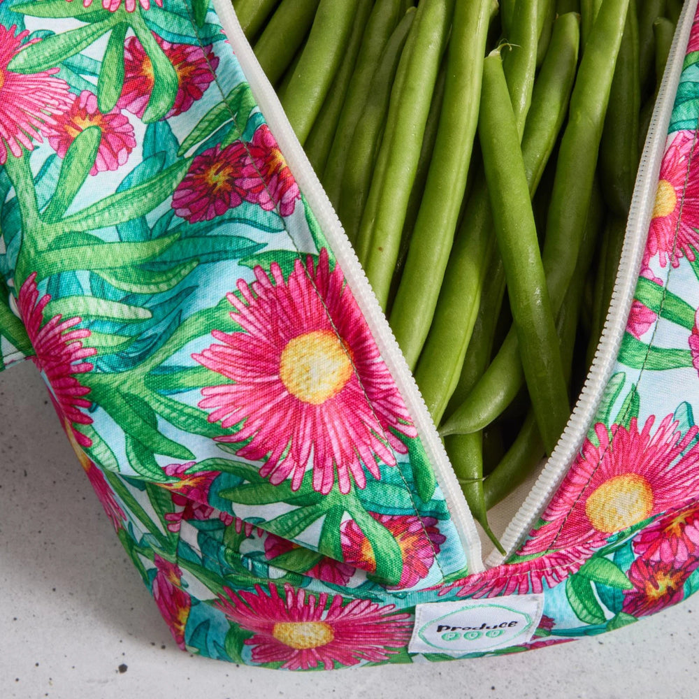 Green beans in a reusable produce bag with floral pattern on a grey surface