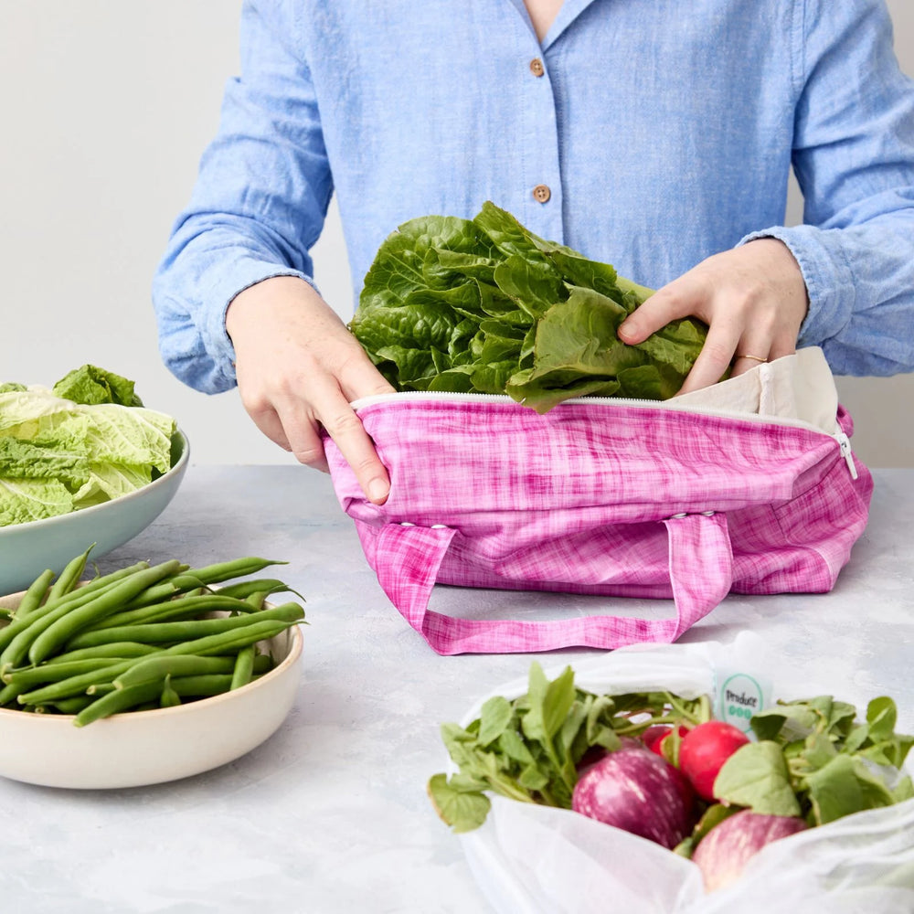 Person using a reusable produce bag with green vegetables in a kitchen