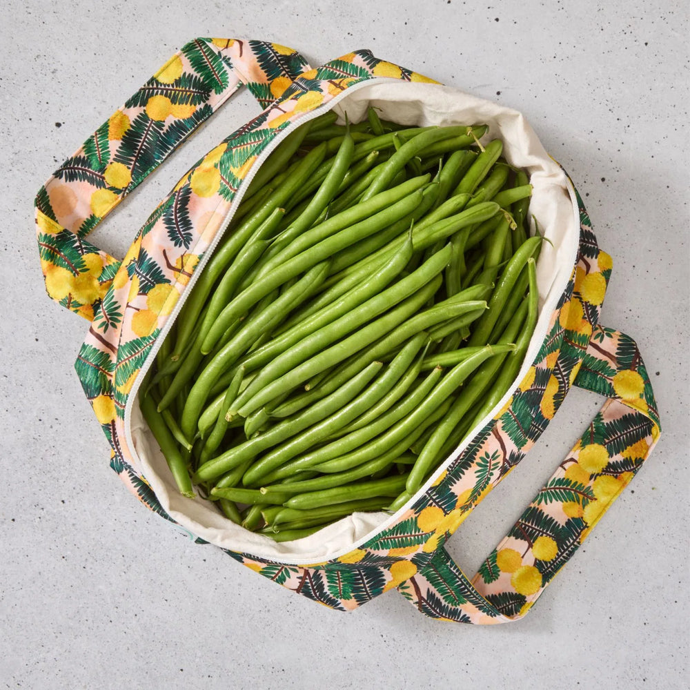 Yellow floral reusable produce bag filled with green beans on a grey surface