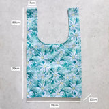 Reusable shopping bag with floral pattern and measurements on a concrete surface