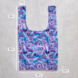 Reusable shopping bag with floral pattern and measurements on a concrete surface