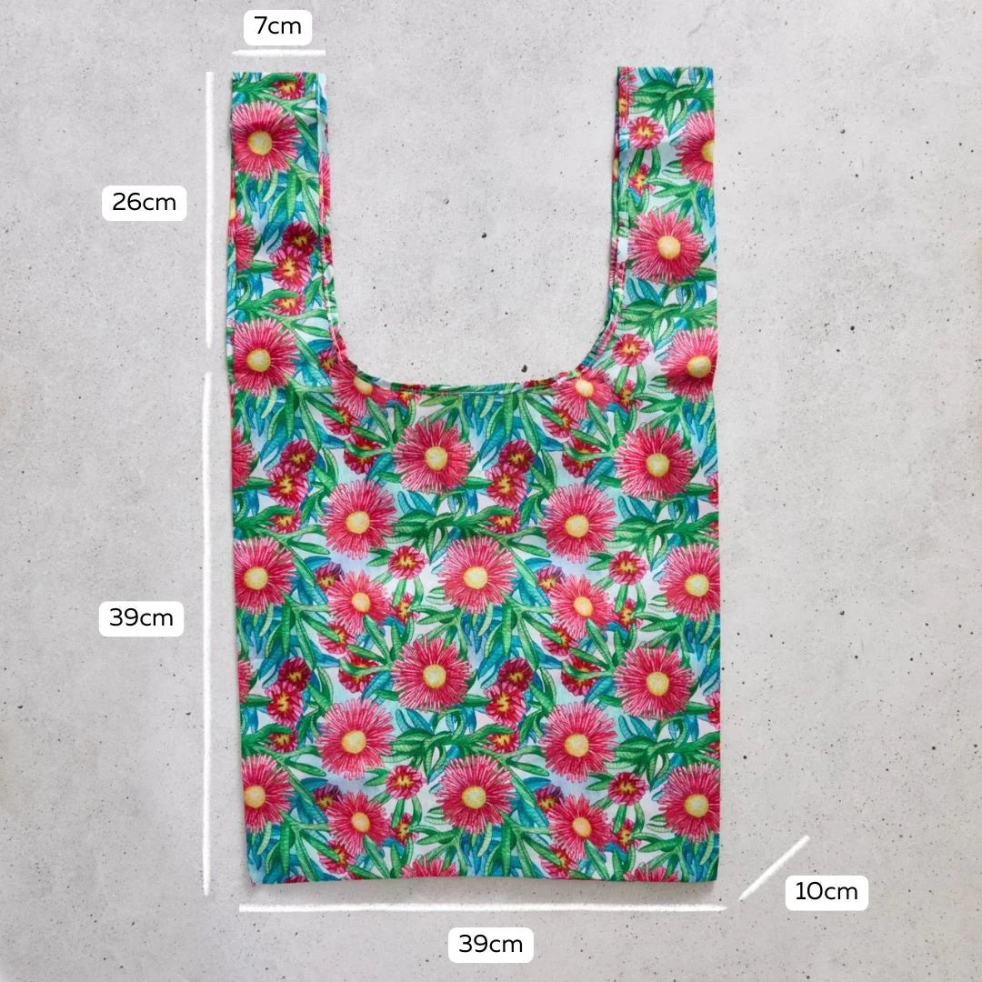 Reusable shopping bag with floral pattern and measurements on a concrete surface