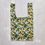 Reusable shopping bag with floral pattern and measurements on a concrete surface