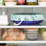 Floral-patterned bowl cover on a blue bowl in the fridge.