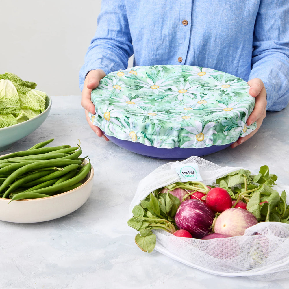 Person holding a reusable bowl cover on a blue bowl