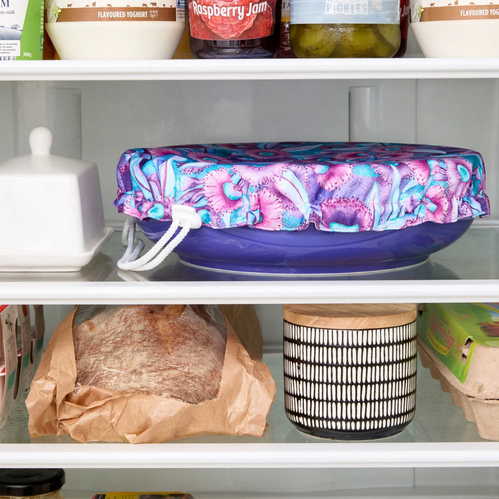 Floral-patterned bowl cover on a blue bowl in the fridge.
