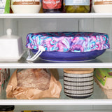 Floral-patterned bowl cover on a blue bowl in the fridge.