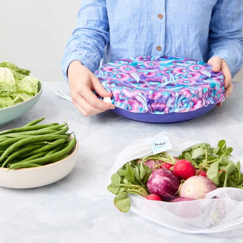 Person holding a reusable bowl cover on a blue bowl