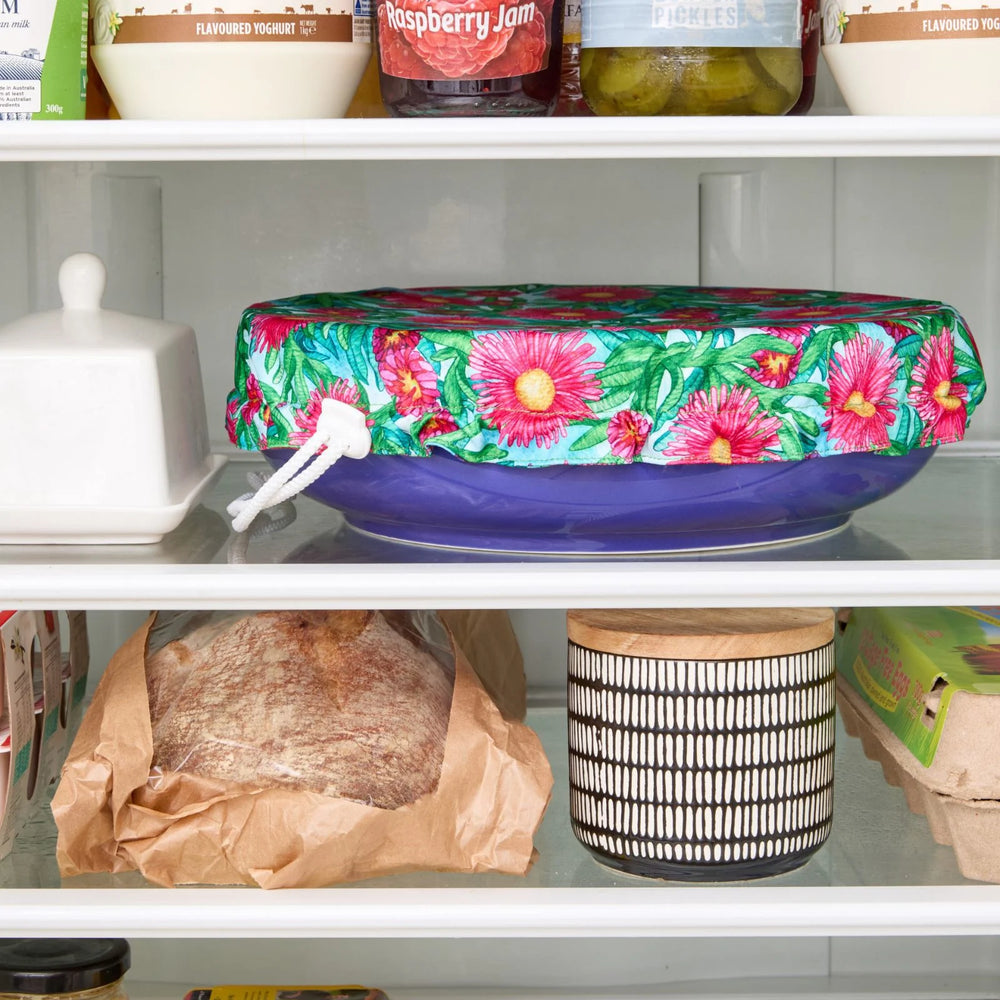 Floral-patterned bowl cover on a blue bowl in the fridge.
