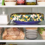 Floral-patterned bowl cover on a blue bowl in the fridge.