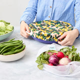 Person holding a reusable bowl cover on a blue bowl