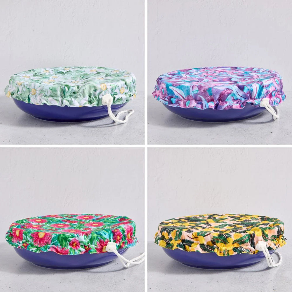 Four floral-patterned reusable bowl covers on a bowls against a light grey background