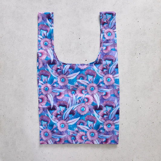 Reusable shopping bag with purple floral pattern on a concrete surface