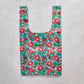 Reusable shopping bag with pink floral pattern on a concrete surface