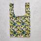 Reusable shopping bag with yellow floral pattern on a concrete surface
