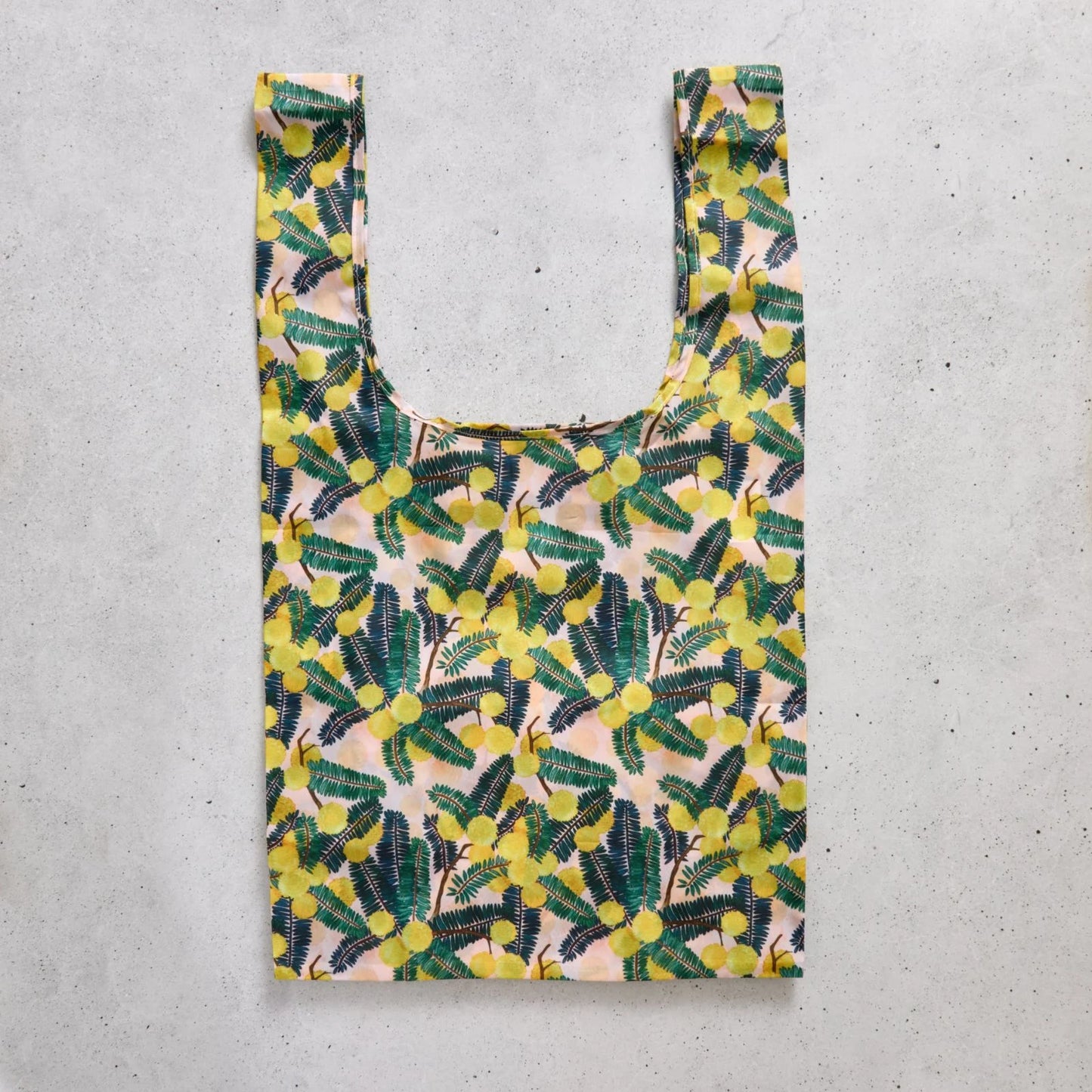 Reusable shopping bag with yellow floral pattern on a concrete surface