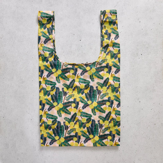 Reusable shopping bag with yellow floral pattern on a concrete surface