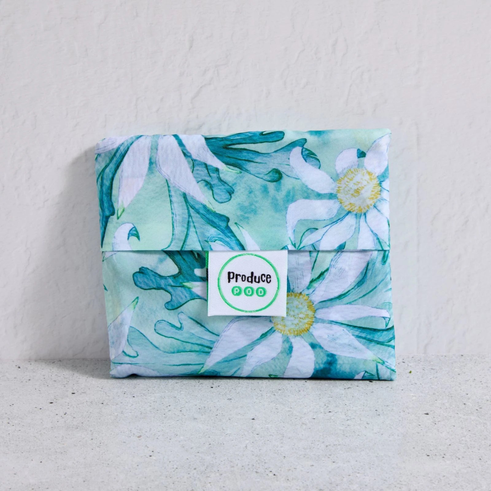 Floral-patterned shopper bag folded up with a visible brand label on a light background