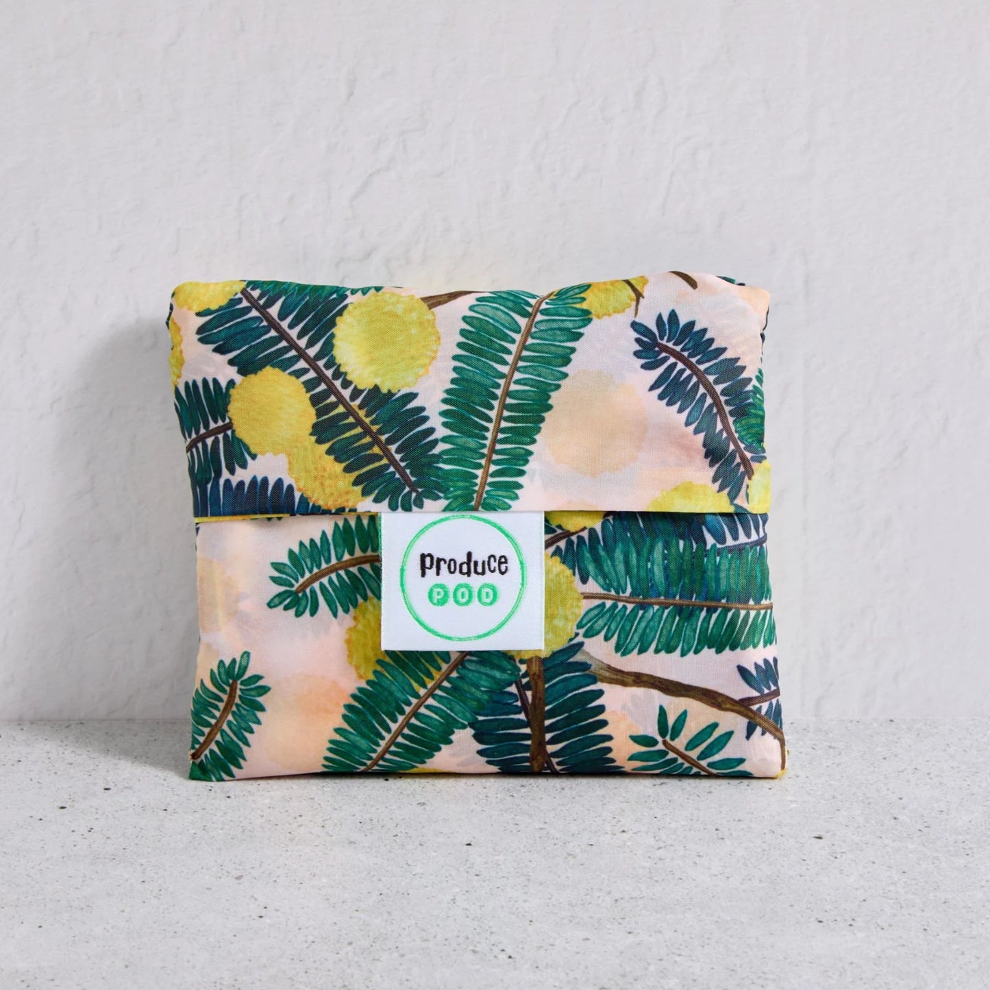 Floral-patterned shopper bag folded up with a visible brand label on a light background