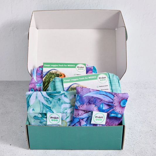 Open gift box containing reusable produce bags with visible branding on a light grey background