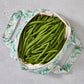 Green floral reusable produce bag filled with green beans on a grey surface