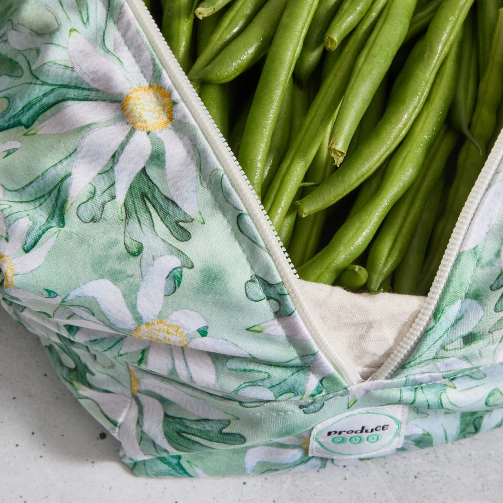 Green beans in a reusable produce bag with floral pattern on a grey surface