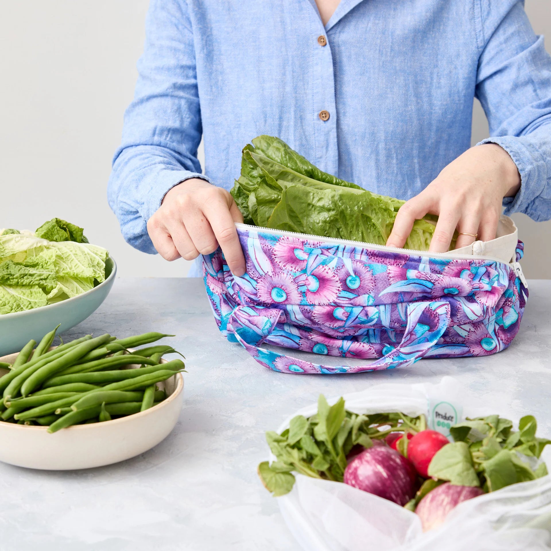 Person using a reusable produce bag with green vegetables in a kitchen