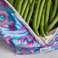 Green beans in a reusable produce bag with floral pattern on a grey surface