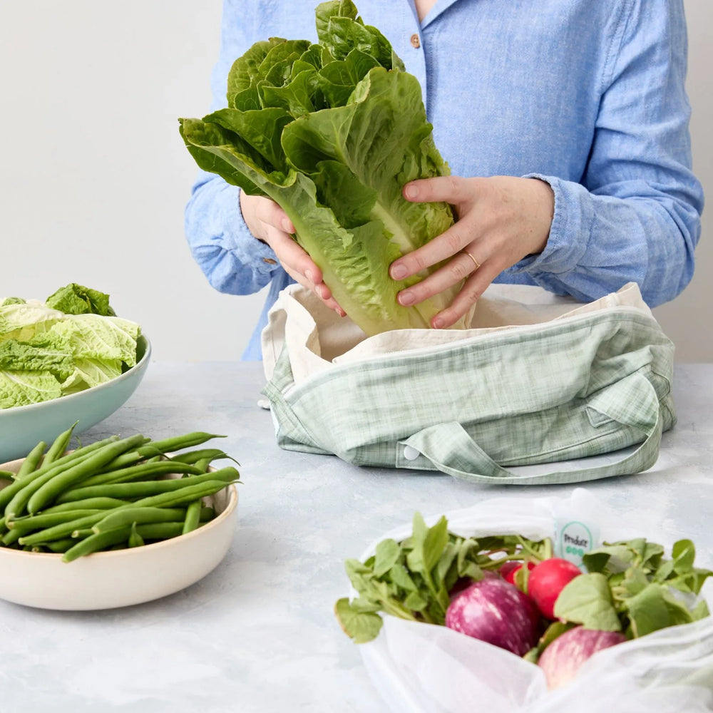 Person using a reusable produce bag with green vegetables in a kitchen