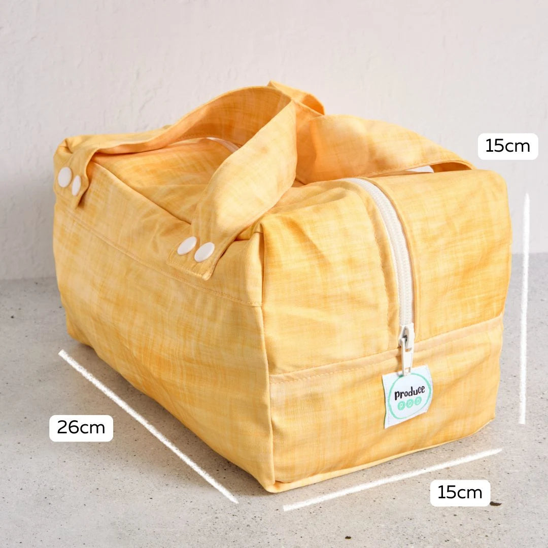 Yellow reusable produce bag with measurements on a grey background