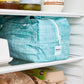 Teal reusable produce bag on a fridge shelf