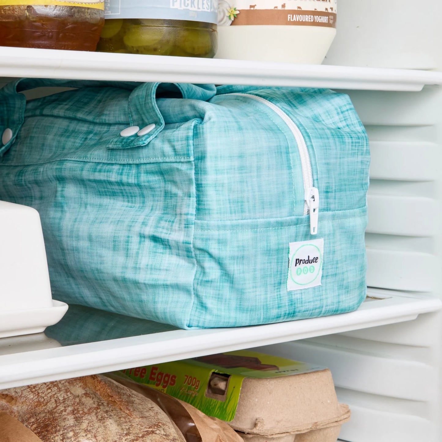 Teal reusable produce bag on a fridge shelf