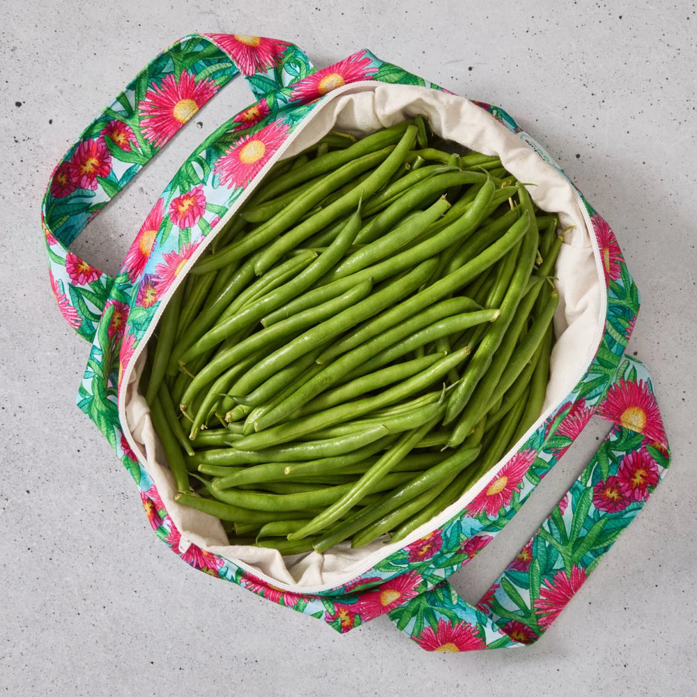 Pink floral reusable produce bag filled with green beans on a grey surface