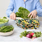 Person using a reusable produce bag with green vegetables in a kitchen