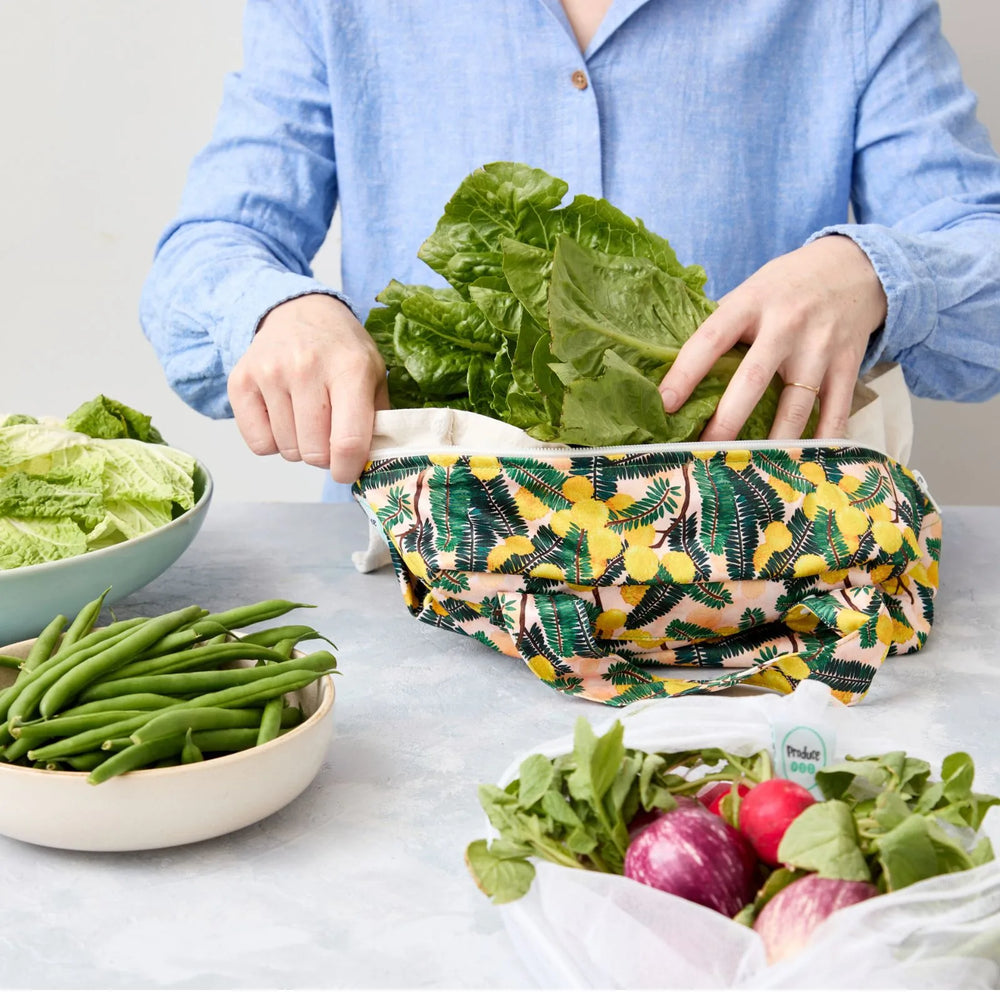 Person using a reusable produce bag with green vegetables in a kitchen