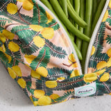Green beans in a reusable produce bag with floral pattern on a grey surface