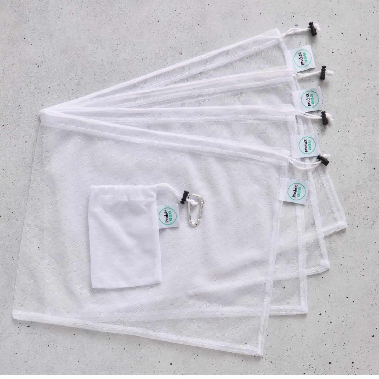Set of four white reusable mesh produce bags with carry pouch on a grey surface