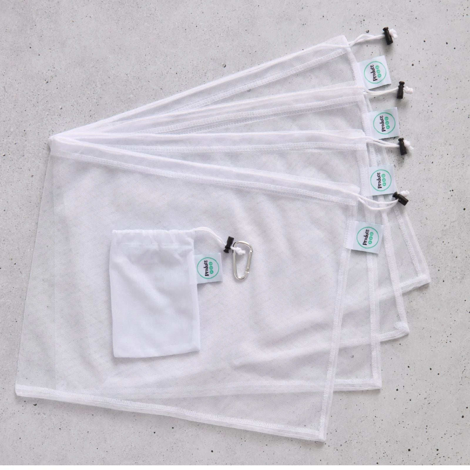 Set of four white reusable mesh produce bags with carry pouch on a grey surface