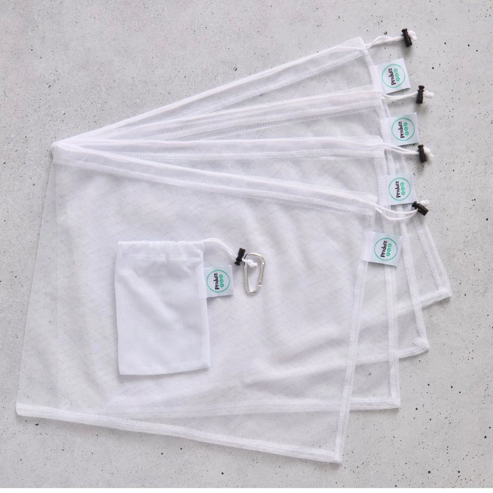 Set of four white reusable mesh produce bags with carry pouch on a grey surface