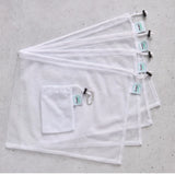 Set of four white reusable mesh produce bags with carry pouch on a grey surface