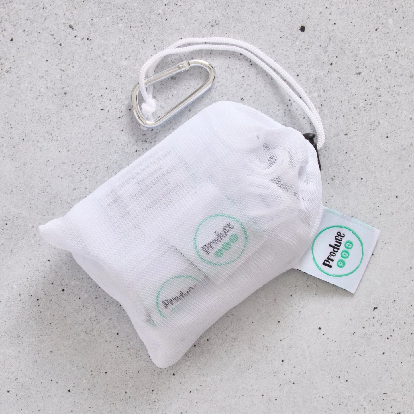 White drawstring bag with carabiner and 'Produce Pod' tags on a grey surface