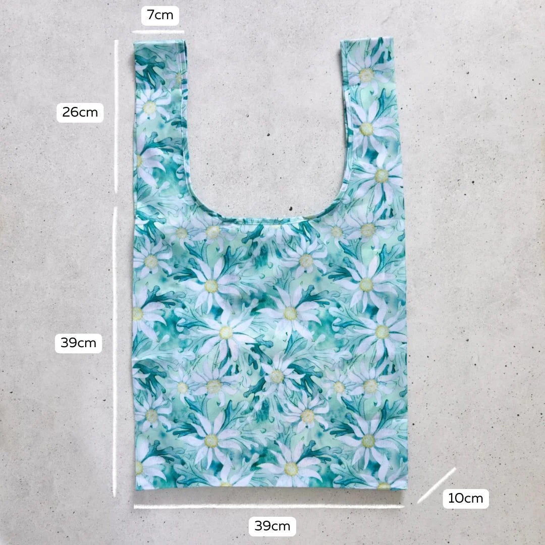 Reusable shopping bag with floral pattern and measurements on a concrete surface