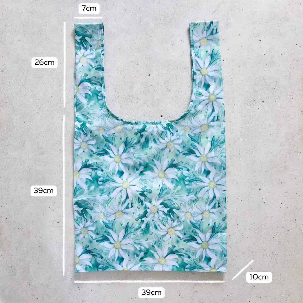 Reusable shopping bag with floral pattern and measurements on a concrete surface