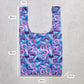 Reusable shopping bag with floral pattern and measurements on a concrete surface
