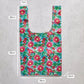Reusable shopping bag with floral pattern and measurements on a concrete surface