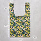 Reusable shopping bag with floral pattern and measurements on a concrete surface