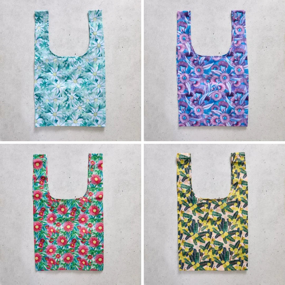 Four floral-patterned reusable shopper bags on a concrete surface