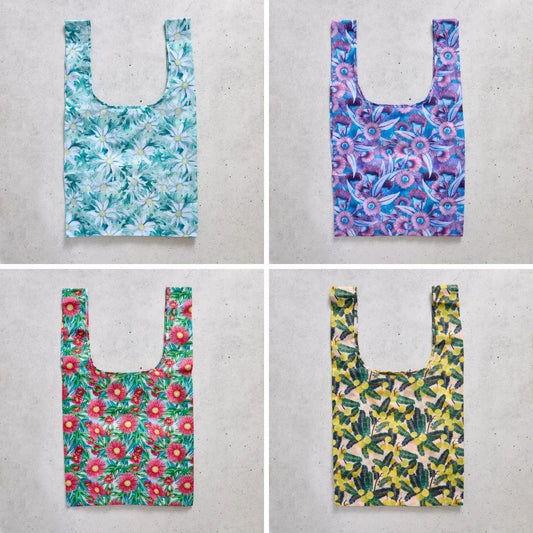 Four floral-patterned reusable shopper bags on a concrete surface